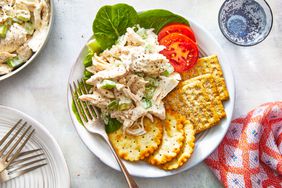 Homemade Chicken Salad on a white plate with lettuce leaves, tomatoes, and crackers