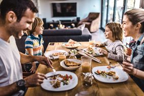 Young happy family talking while having lunch at dining table.