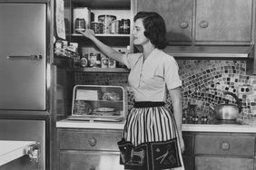 Vintage Photo of Woman Wearing Apron Near Kitchen Cabinets