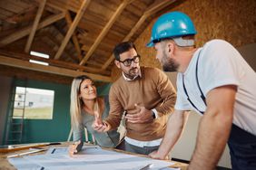 couple talking to a contractor with hardhat on