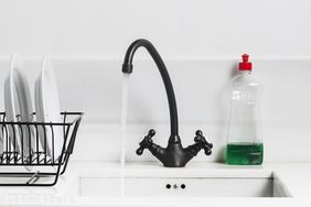 A sink and tap and washing up liquid in a white clean and organised sink and kitchen.