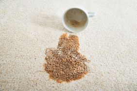 Close-up of coffee spilling from cup on carpet