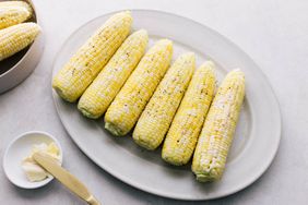 boiled corn on the cob on a platter with salt and pepper