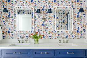 Bathroom with blue cabinets and patterned wallpaper