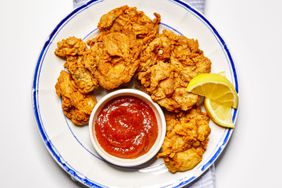 Fried oysters on a plate with lemon wedges and cocktail sauce.